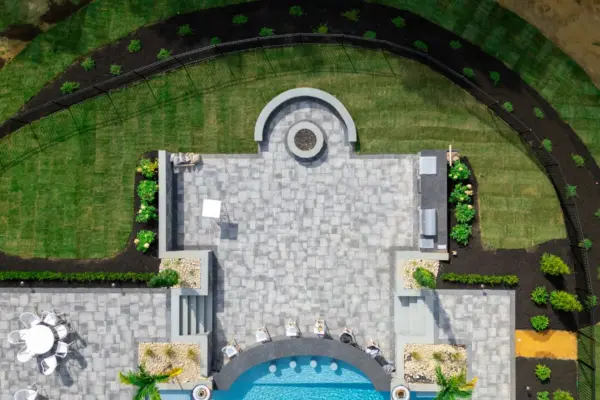 This Colts Neck, NJ backyard was transformed into a luxurious outdoor living space featuring a Nicolock patio, extensive landscaping, privacy screening, custom water and fire features, an outdoor kitchen, and elegant landscape lighting. The design blends durability and elegance, with a high-quality paver patio, soothing water features, and a fully equipped outdoor kitchen for seamless entertaining. Thoughtfully placed landscape lighting and privacy screening create a secluded and inviting atmosphere, making this space perfect for both relaxation and hosting.