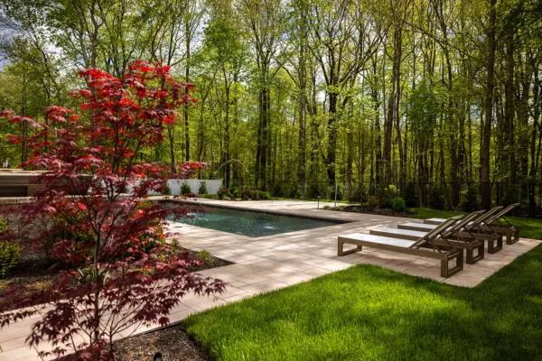 This Old Bridge, NJ backyard was transformed into a luxurious outdoor retreat featuring a raised patio and pool deck, outdoor kitchen, custom pavilion, water features, landscape lighting, fresh sod, and professional landscaping. The design combines durability and elegance, with a fully equipped outdoor kitchen, a shaded pavilion for entertaining, and stunning water features that enhance the space. With low-voltage LED lighting and lush greenery, this backyard is now perfect for both relaxation and hosting.